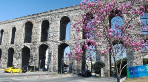 Cyclist on painted green bike lane under two-tier Valens Aqueduct arches in central Istanbul