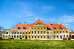 Pastel baroque houses and a church tower mirrored in the calm Danube at golden hour, Vukovar