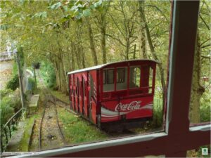 Red wooden funicular car climbs Monte Igueldo with ocean behind