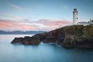 White Fanad Head lighthouse tower with keeper cottages against a blue Irish sea