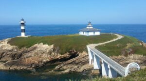 Striped lighthouse on Isla Pancha linked by a small bridge to Galicia’s mainland