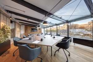 Interior of a wood-panelled coworking hub near Brienz—cowbells hang decoratively, laptops glow on long tables