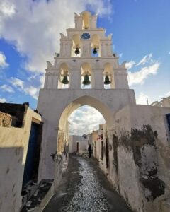 Stone bell-tower archway leading into Megalochori’s central lane