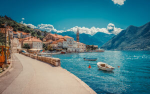 Turquoise harbor of Capraia dotted with sailboats, steep vine-covered hills rising behind