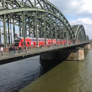 Solaris train crossing Cologne’s Hohenzollern Bridge with rooftop panels gleaming